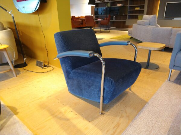 Scylla - laag - design fauteuil van Leolux met ribstof bekleding, lederen armleuning en verchroomd frame. Nu in de showroomsale bij Gulden Interieur.